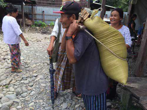 A flood victim (a believer from Bethany Brethen Assembly in Kale) carries a bag of rice