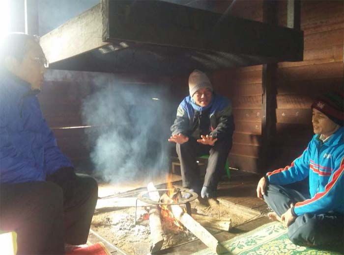 Brother Kap and two brothers sit by fire in Putao, Kachin State.